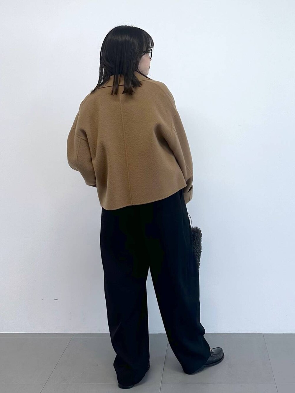 グレー系のハンドバッグ、ブラック系のその他パンツ、ホワイト系のニット/セーターを着用したレディースの冬コーディネートの3枚目の写真