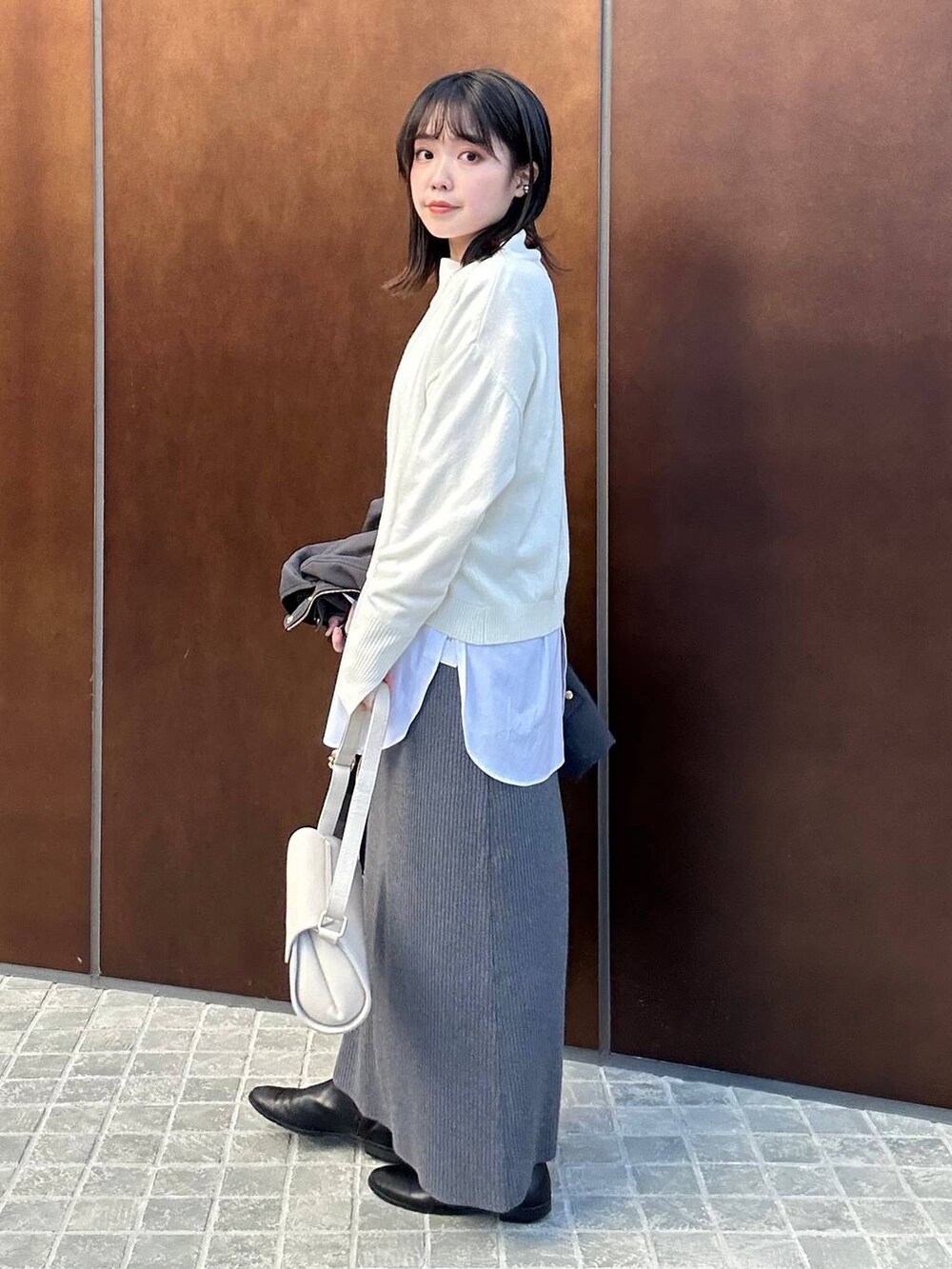 ホワイト系のシャツ/ブラウス、グレー系のスカート、ホワイト系のニット/セーターを着用したレディースの冬コーディネートの2枚目の写真