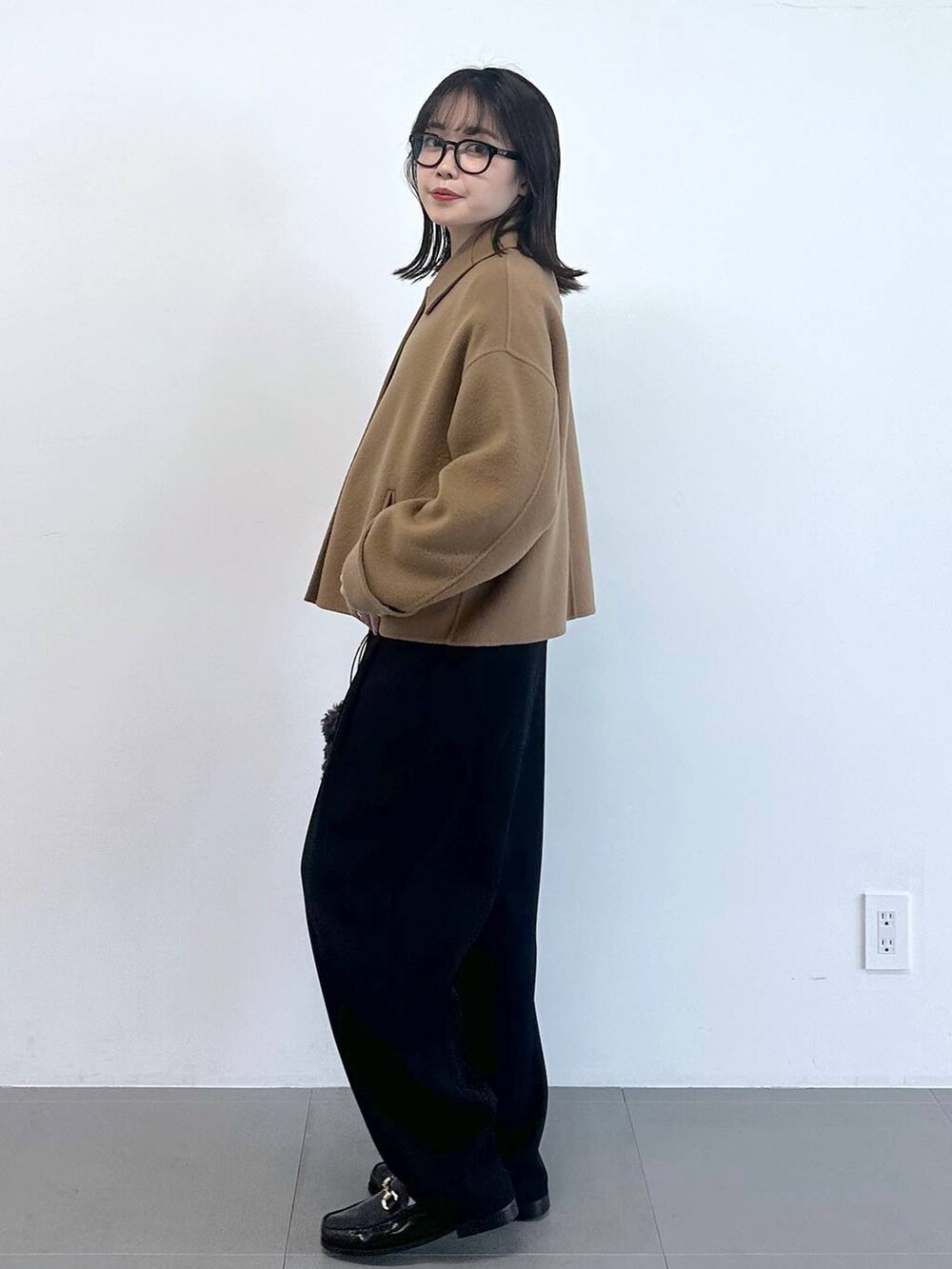 グレー系のハンドバッグ、ブラック系のその他パンツ、ホワイト系のニット/セーターを着用したレディースの冬コーディネートの2枚目の写真