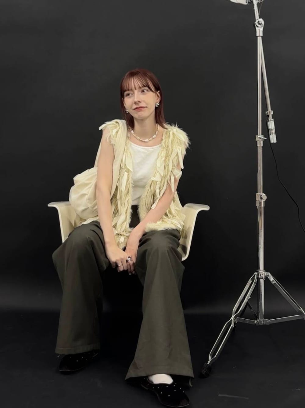 ホワイト系のベスト、ホワイト系のショルダーバッグ、ブラウン系のパンプスを着用したレディースの夏コーディネートの2枚目の写真