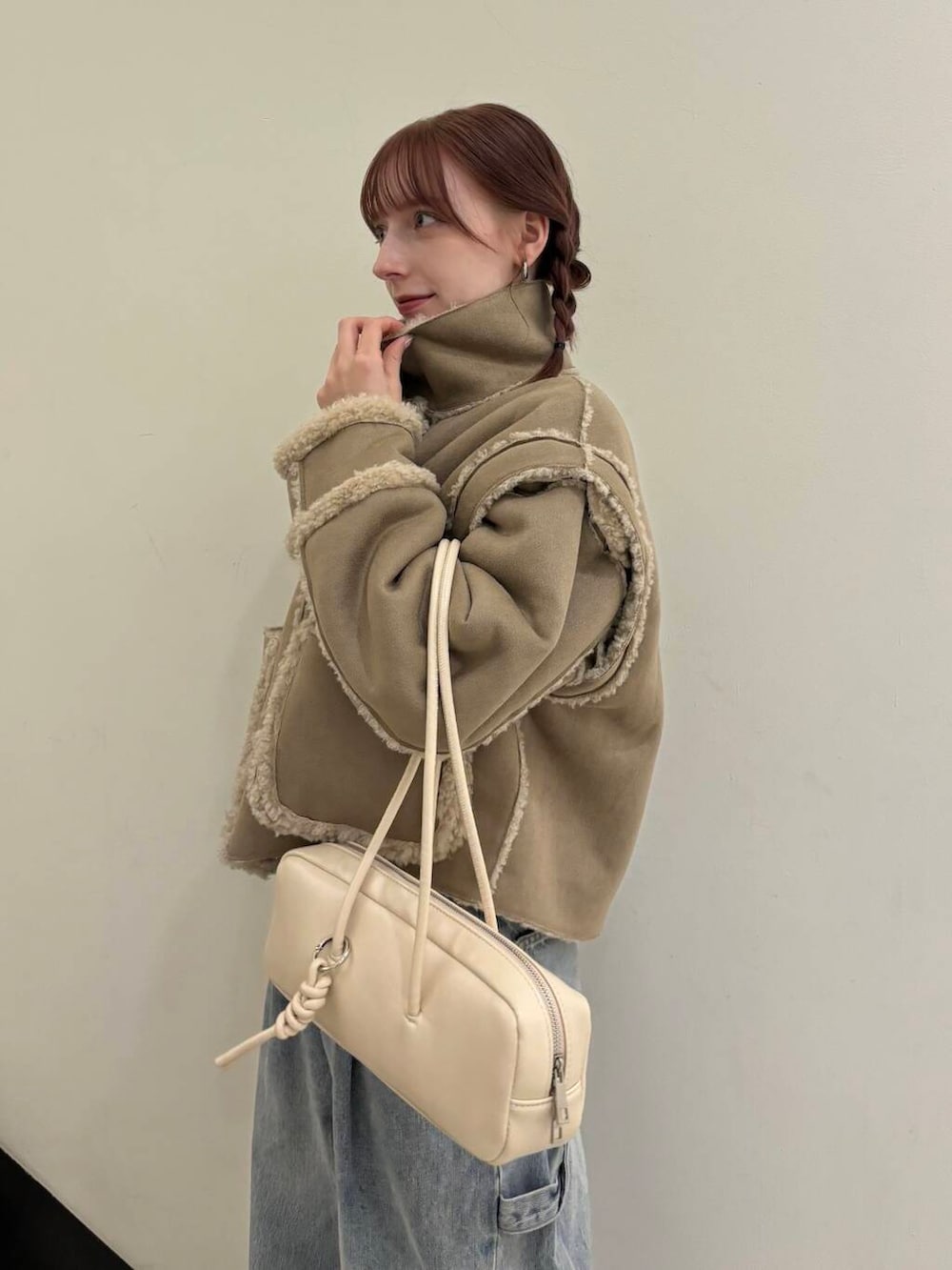 ブルー系のデニムパンツ、ベージュ系のその他アウター、ホワイト系のショルダーバッグを着用したレディースの秋コーディネートの4枚目の写真