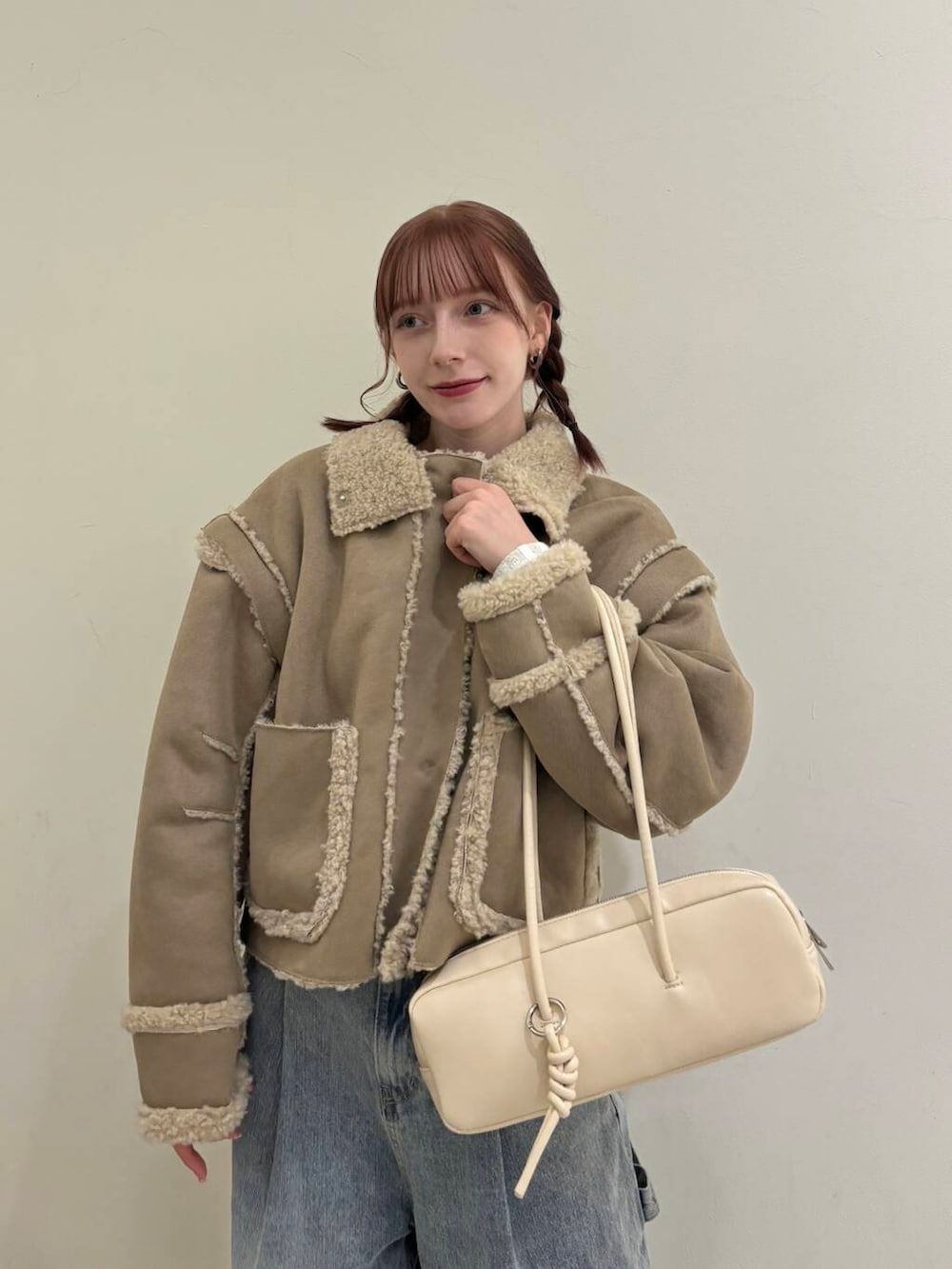 ブルー系のデニムパンツ、ベージュ系のその他アウター、ホワイト系のショルダーバッグを着用したレディースの秋コーディネートの2枚目の写真