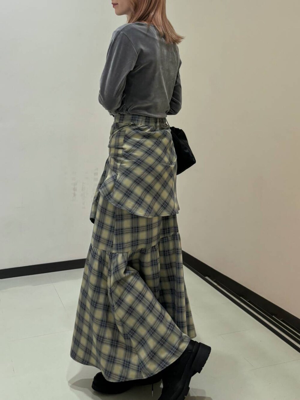 ブラック系のブーツ、ブラック系のハンドバッグ、ベージュ系のスカートを着用したレディースの冬コーディネートの2枚目の写真