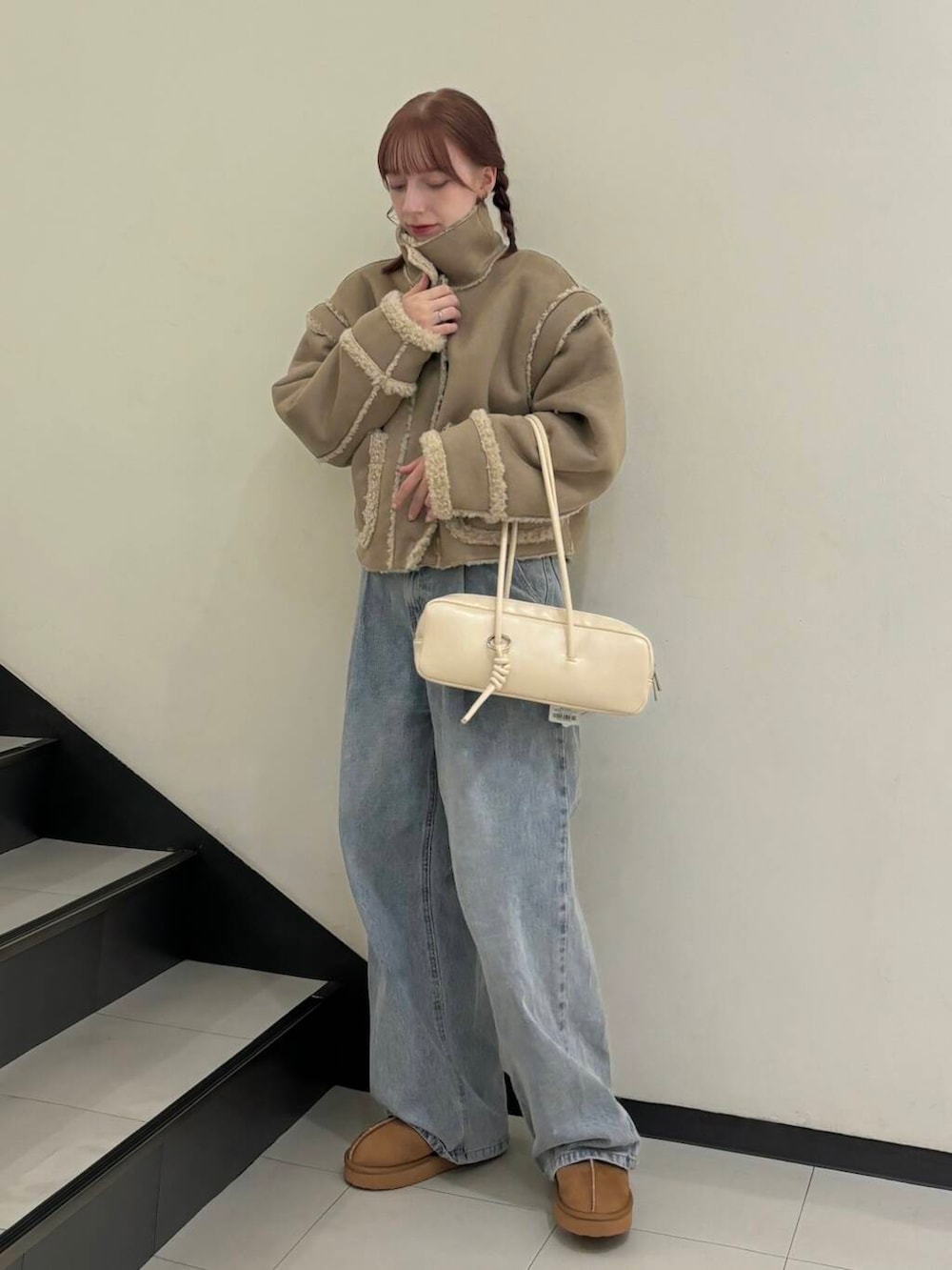 ブルー系のデニムパンツ、ベージュ系のその他アウター、ホワイト系のショルダーバッグを着用したレディースの秋コーディネートの3枚目の写真