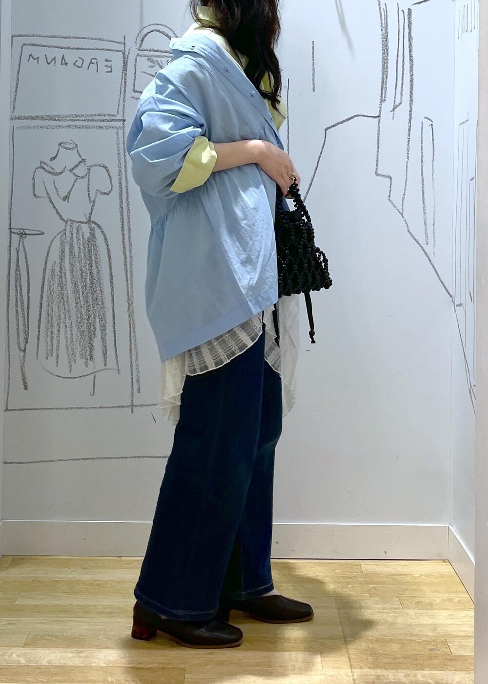 ブルー系のデニムパンツ、ブラック系のパンプス、ホワイト系のスカートを着用したレディースの春コーディネートの5枚目の写真