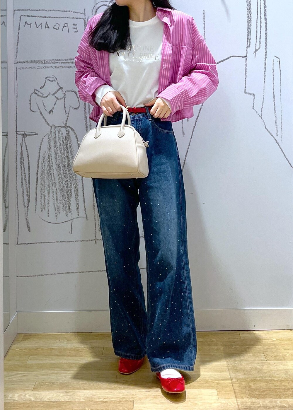 ブルー系のデニムパンツ、ベージュ系のボストンバッグ、ピンク系のシャツ/ブラウスを着用したレディースの春コーディネートの2枚目の写真