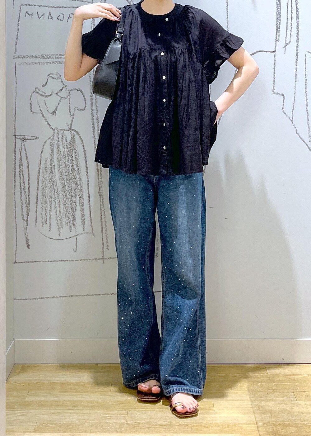 ブラック系のハンドバッグ、ブルー系のデニムパンツ、ブラウン系のサンダルを着用したレディースの夏コーディネートの2枚目の写真