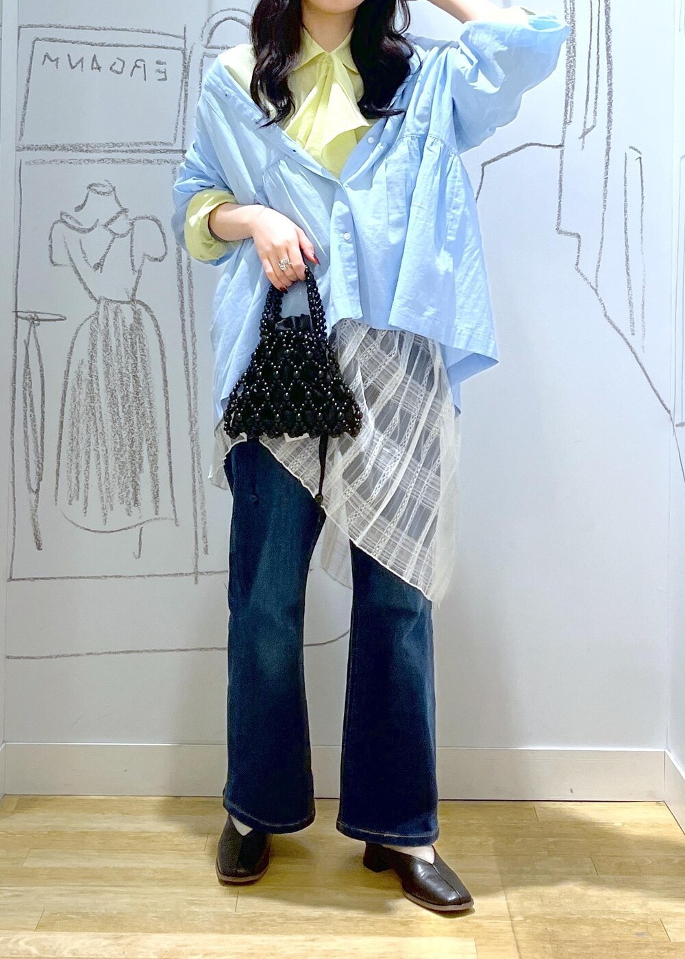 ブルー系のデニムパンツ、ブラック系のパンプス、ホワイト系のスカートを着用したレディースの春コーディネートの2枚目の写真