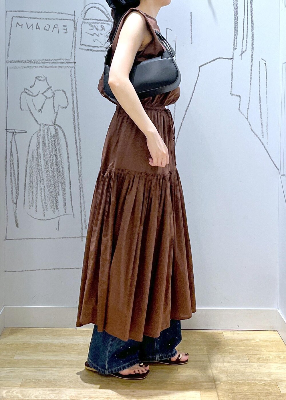 ブラック系のハンドバッグ、ブルー系のデニムパンツ、ブラウン系のサンダルを着用したレディースの夏コーディネートの3枚目の写真