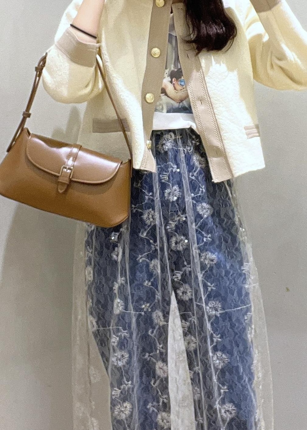 ブルー系のデニムパンツ、ホワイト系のカーディガン/ボレロ、ホワイト系のスカートを着用したレディースの秋コーディネートの4枚目の写真