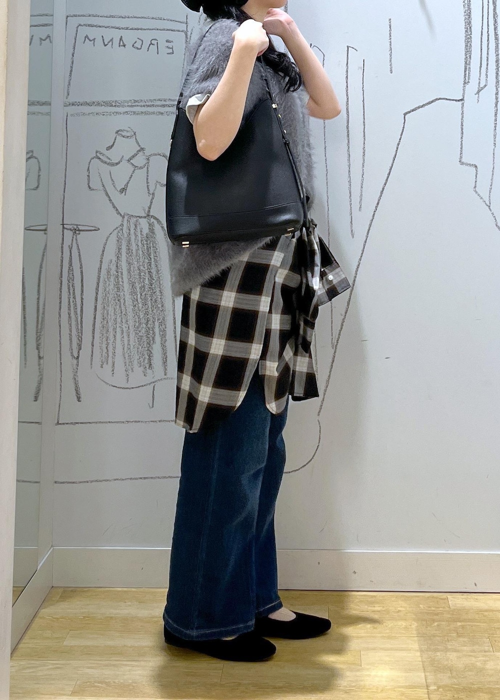 ブルー系のデニムパンツ、ブラック系のショルダーバッグ、グレー系のベストを着用したレディースの夏コーディネートの3枚目の写真