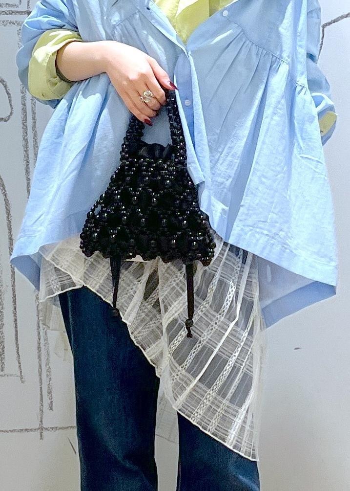 ブルー系のデニムパンツ、ブラック系のパンプス、ホワイト系のスカートを着用したレディースの春コーディネートの7枚目の写真