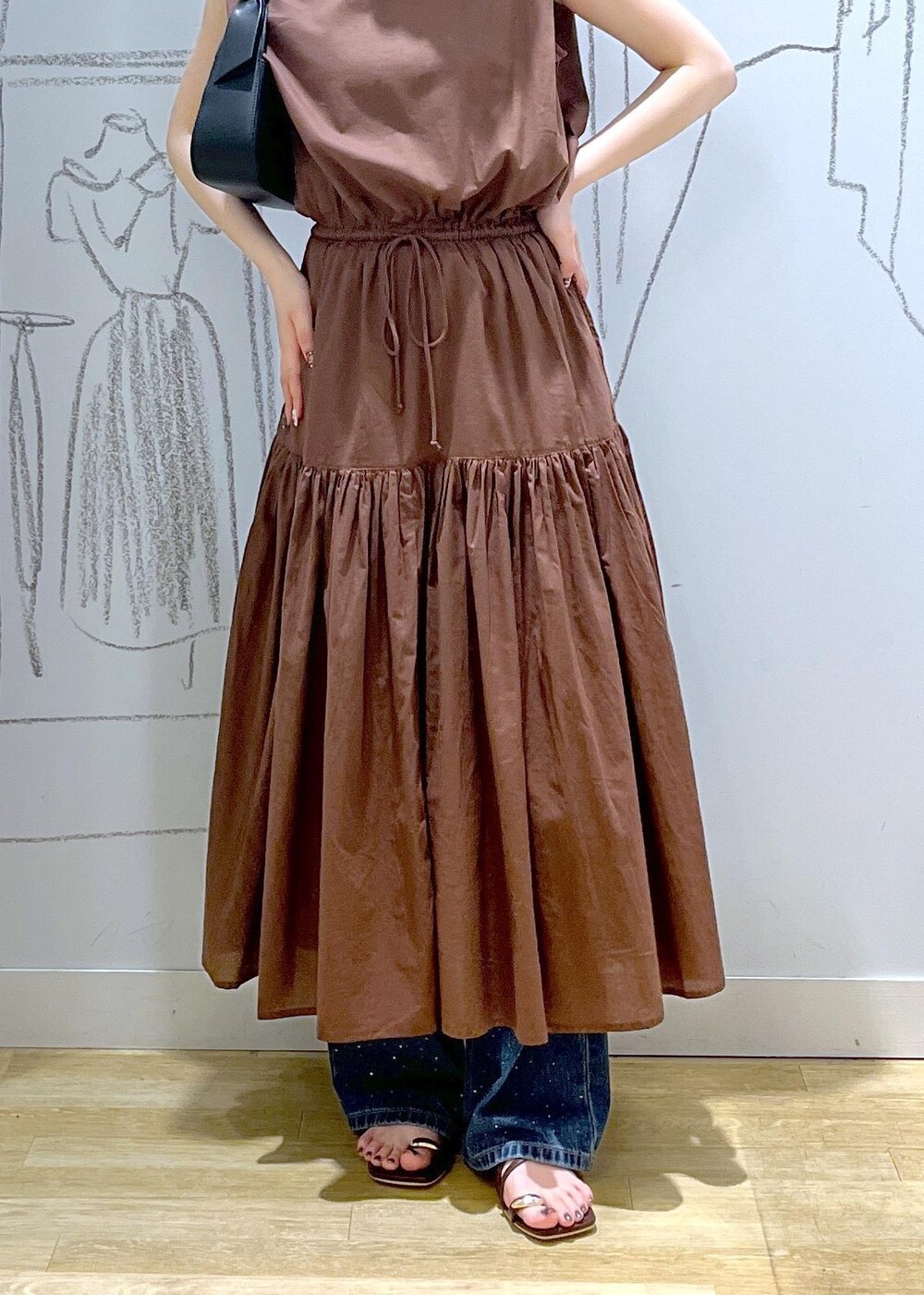 ブラック系のハンドバッグ、ブルー系のデニムパンツ、ブラウン系のサンダルを着用したレディースの夏コーディネートの7枚目の写真