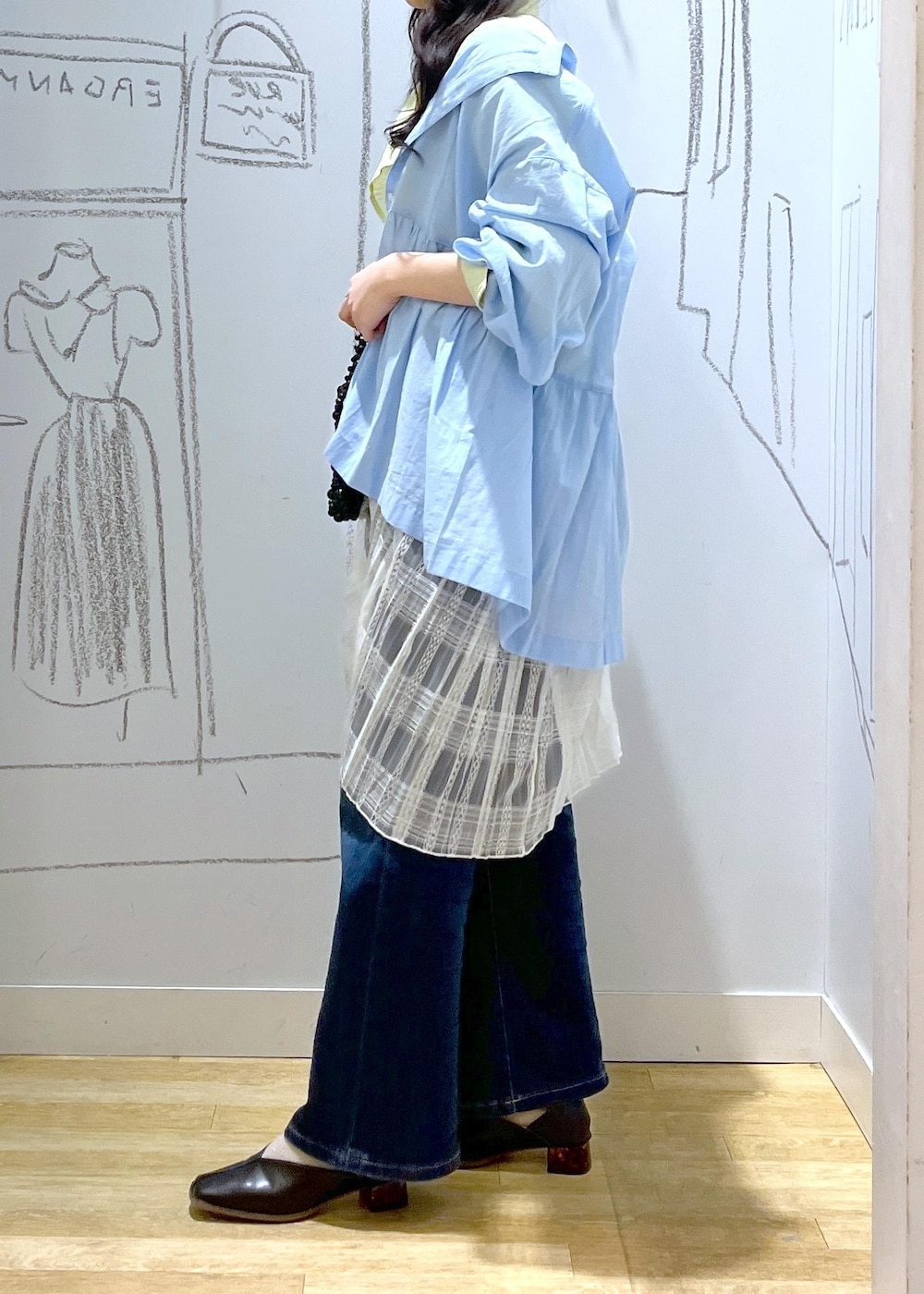 ブルー系のデニムパンツ、ブラック系のパンプス、ホワイト系のスカートを着用したレディースの春コーディネートの3枚目の写真