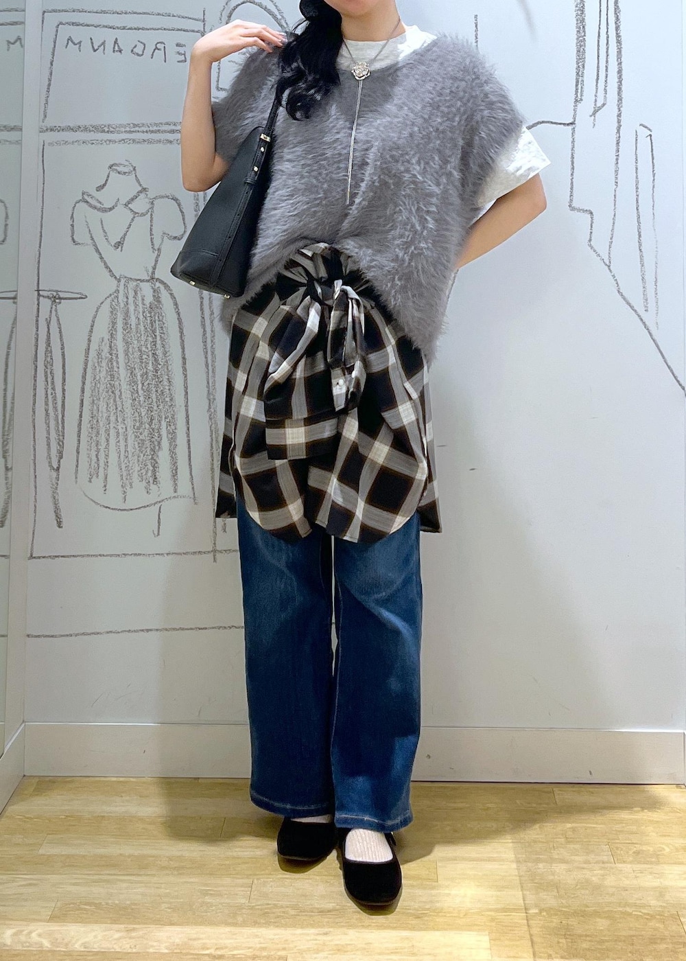 ブルー系のデニムパンツ、ブラック系のショルダーバッグ、グレー系のベストを着用したレディースの夏コーディネートの2枚目の写真