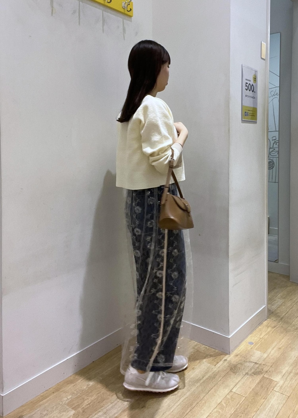 ブルー系のデニムパンツ、ホワイト系のカーディガン/ボレロ、ホワイト系のスカートを着用したレディースの秋コーディネートの2枚目の写真