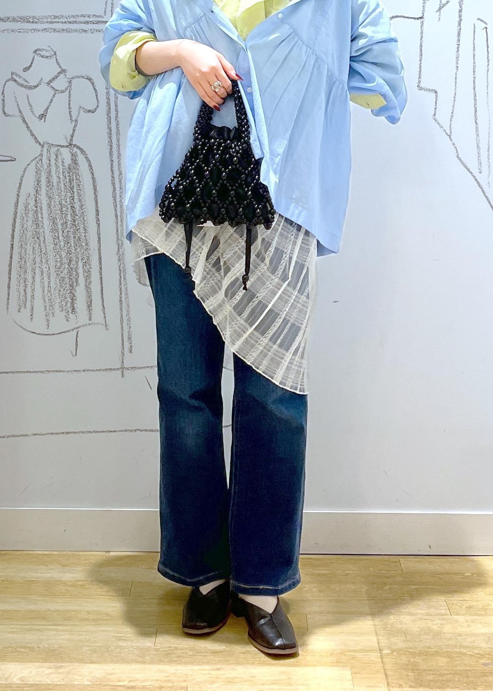 ブルー系のデニムパンツ、ブラック系のパンプス、ホワイト系のスカートを着用したレディースの春コーディネートの6枚目の写真