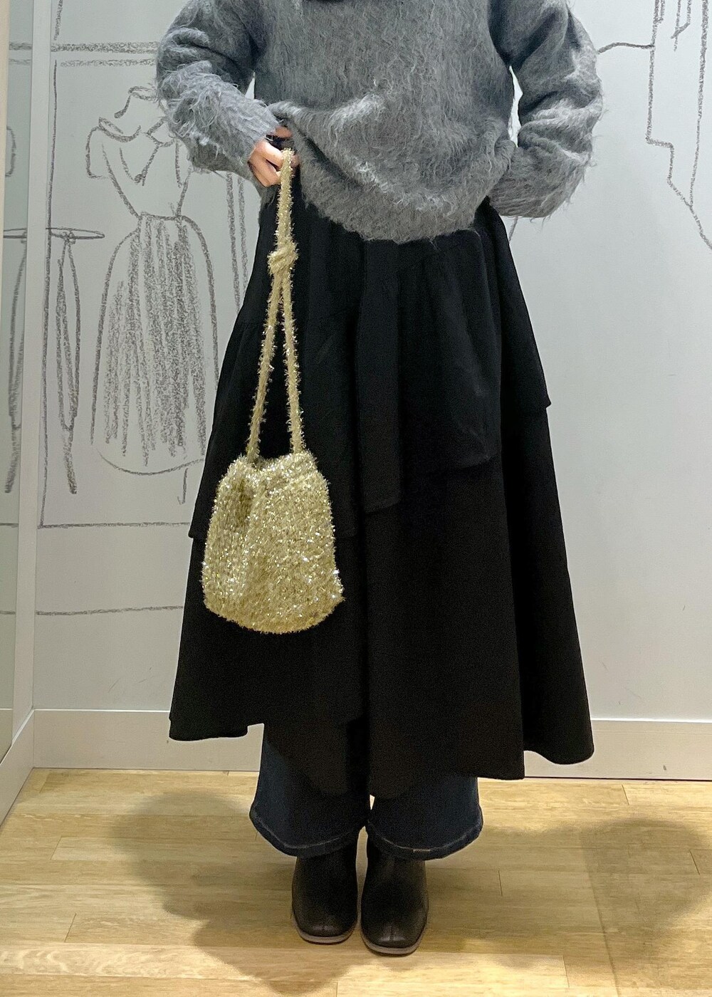 ブルー系のデニムパンツ、ブラック系のブーツ、ブラック系のスカートを着用したレディースの冬コーディネートの6枚目の写真