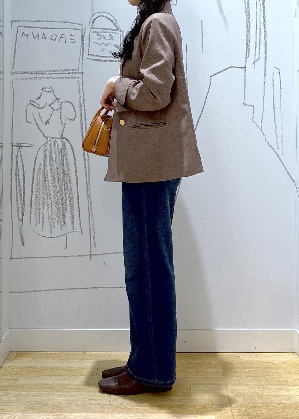 ブルー系のデニムパンツ、ベージュ系のテーラードジャケット、イエロー系のショルダーバッグを着用したレディースの秋コーディネートの3枚目の写真