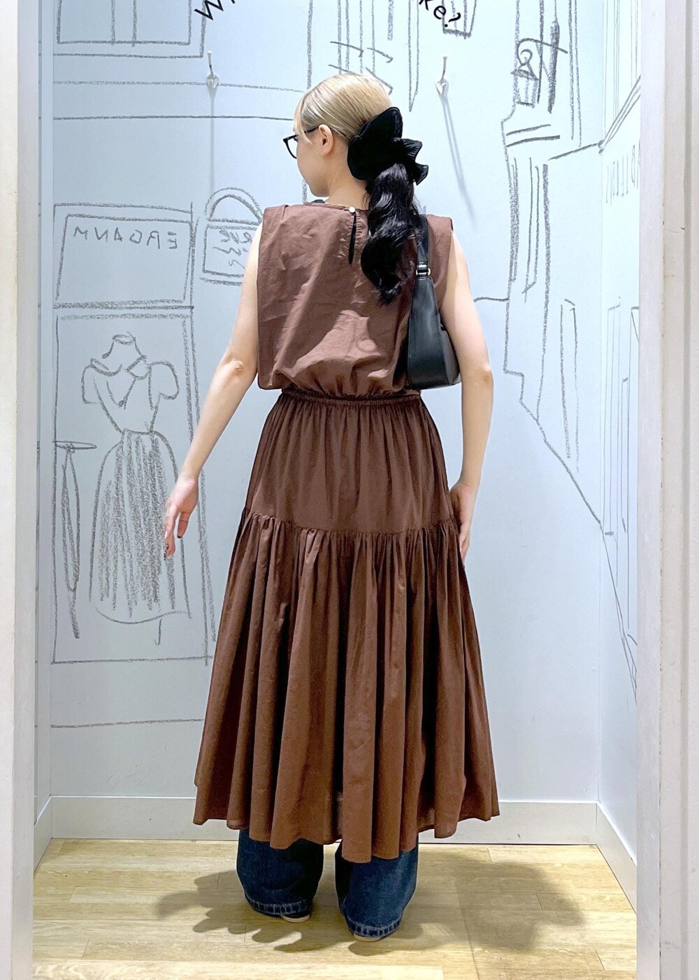 ブラック系のハンドバッグ、ブルー系のデニムパンツ、ブラウン系のサンダルを着用したレディースの夏コーディネートの4枚目の写真