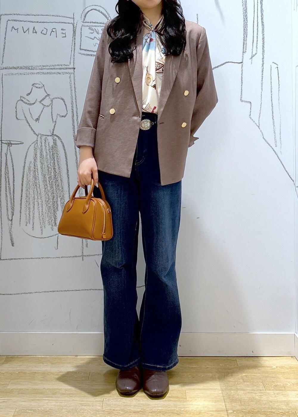 ブルー系のデニムパンツ、ベージュ系のテーラードジャケット、イエロー系のショルダーバッグを着用したレディースの秋コーディネートの2枚目の写真