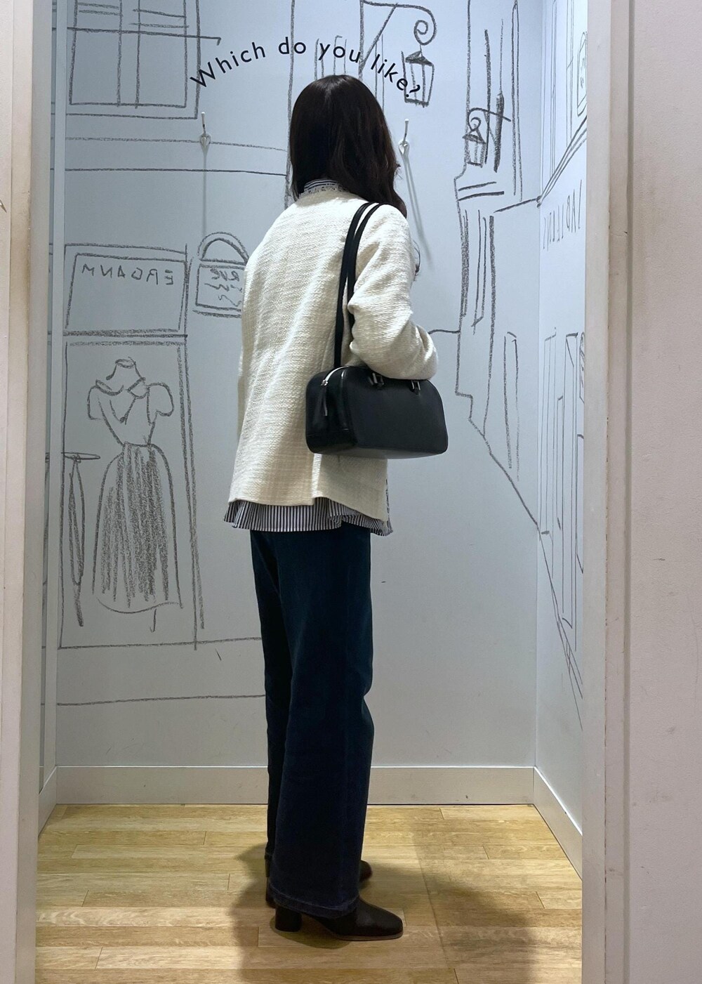 ブルー系のデニムパンツ、ブラック系のブーツ、ブラック系のボストンバッグを着用したレディースの冬コーディネートの2枚目の写真