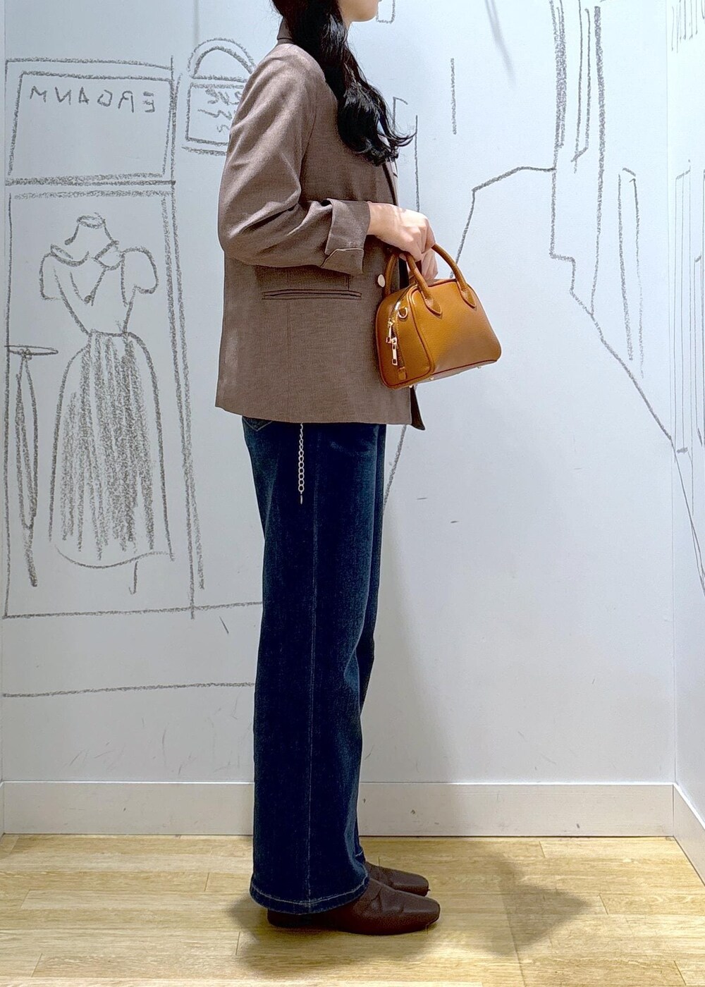 ブルー系のデニムパンツ、ベージュ系のテーラードジャケット、イエロー系のショルダーバッグを着用したレディースの秋コーディネートの5枚目の写真
