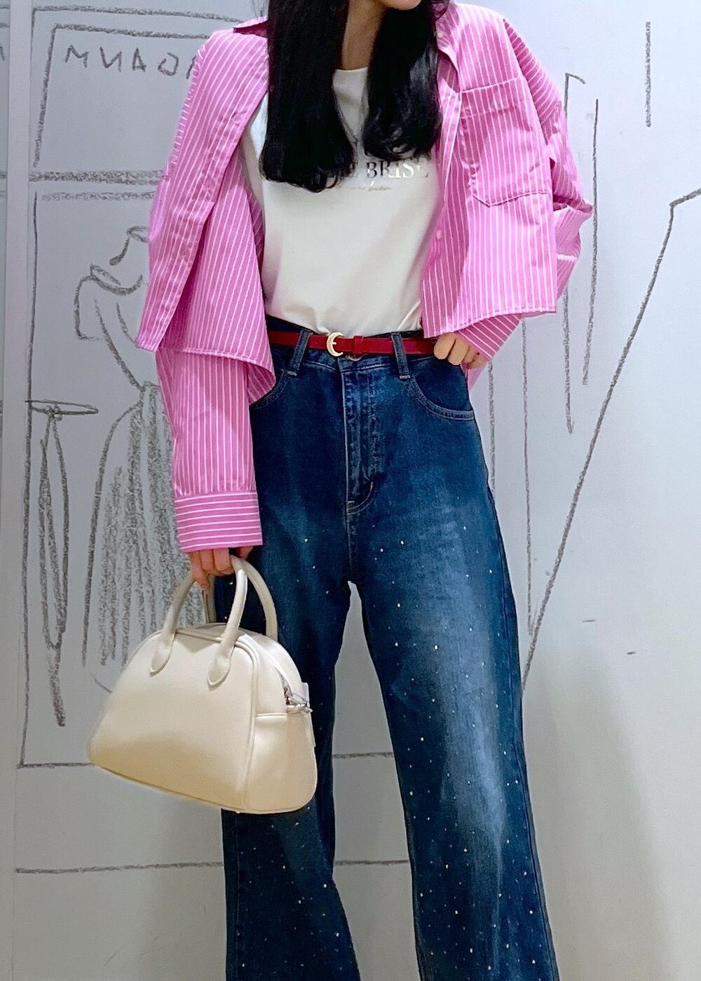 ブルー系のデニムパンツ、ベージュ系のボストンバッグ、ピンク系のシャツ/ブラウスを着用したレディースの春コーディネートの6枚目の写真