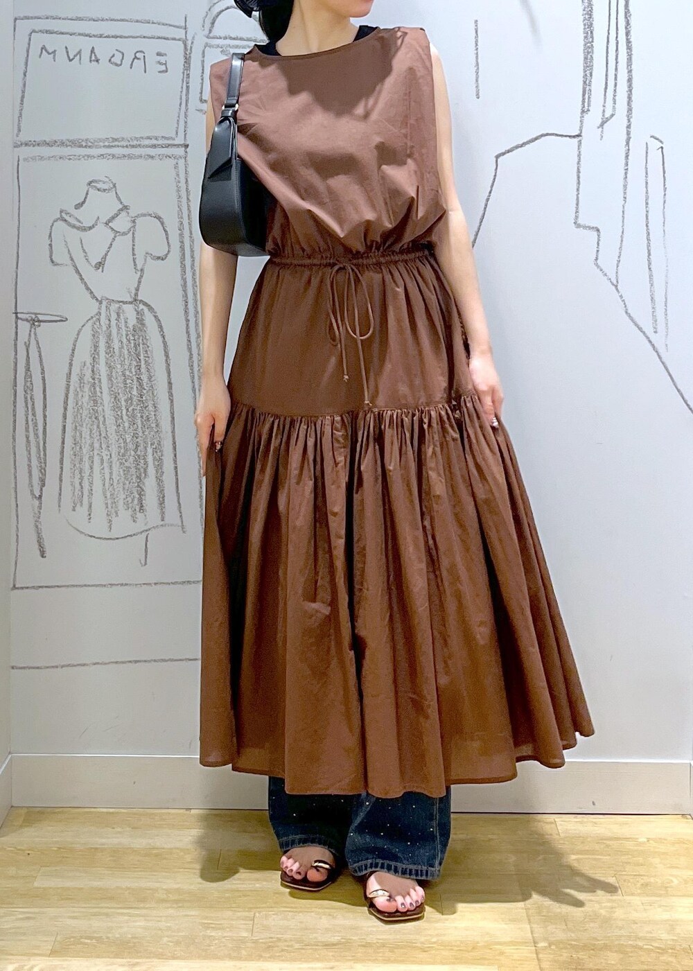 ブラック系のハンドバッグ、ブルー系のデニムパンツ、ブラウン系のサンダルを着用したレディースの夏コーディネートの2枚目の写真