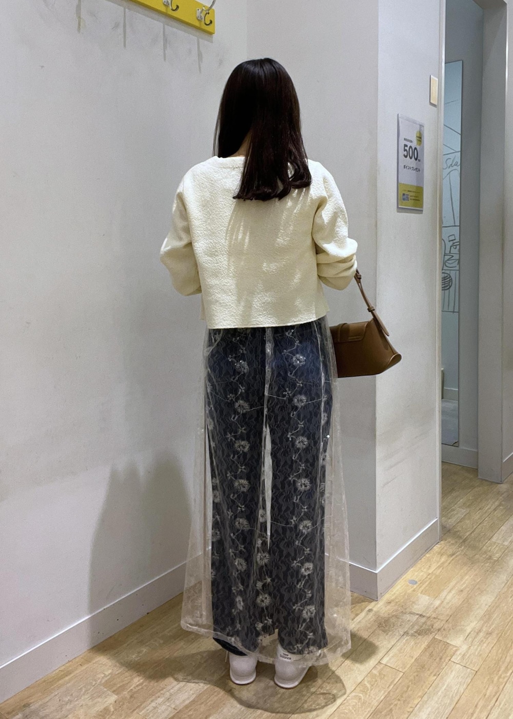 ブルー系のデニムパンツ、ホワイト系のカーディガン/ボレロ、ホワイト系のスカートを着用したレディースの秋コーディネートの3枚目の写真