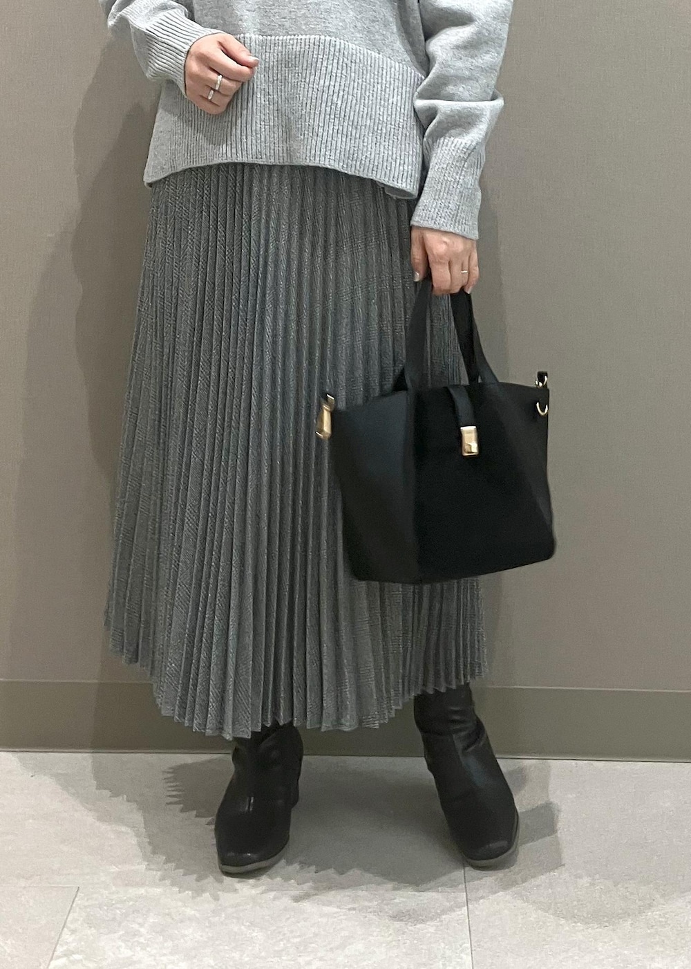 グレー系のニット/セーター、ブラック系のブーツ、ブラック系のトートバッグを着用したレディースの秋コーディネートの6枚目の写真