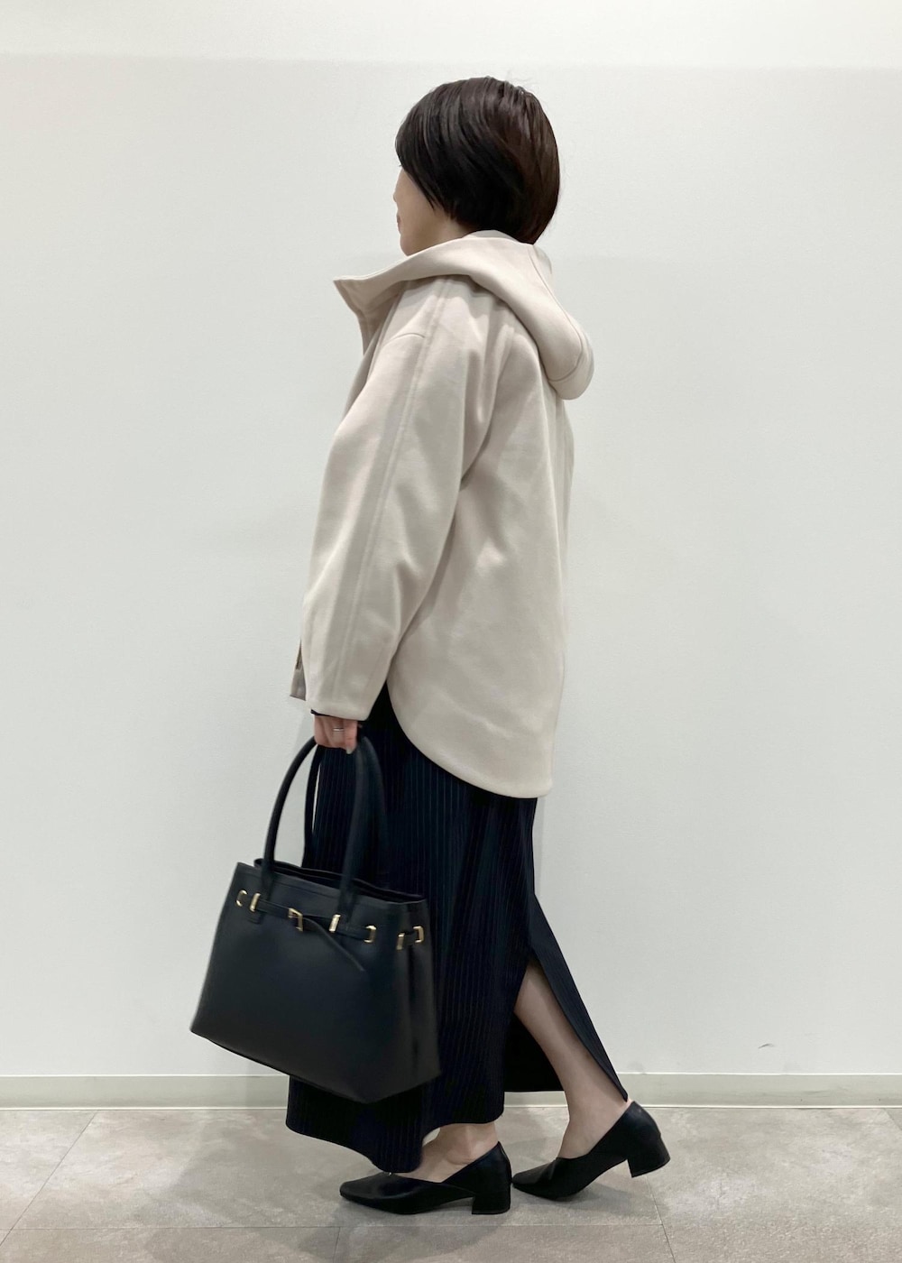 ブラック系のトートバッグ、ブルー系のワンピース、ブラック系のパンプスを着用したレディースの秋コーディネートの3枚目の写真