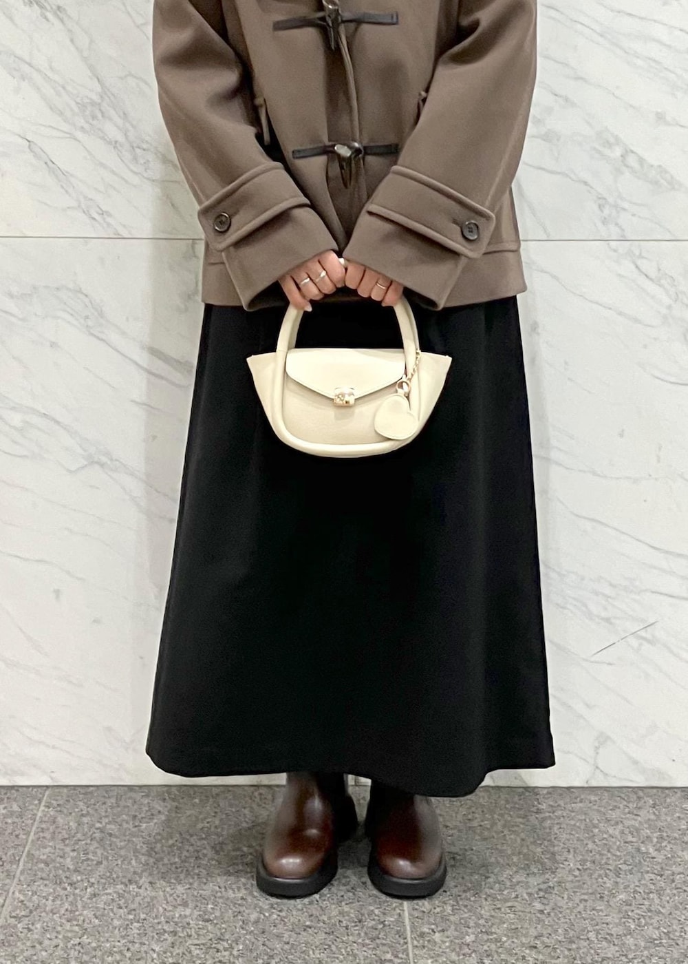 ブラック系のワンピース、ブラウン系のダッフルコート、ホワイト系のニット/セーターを着用したレディースの冬コーディネートの7枚目の写真