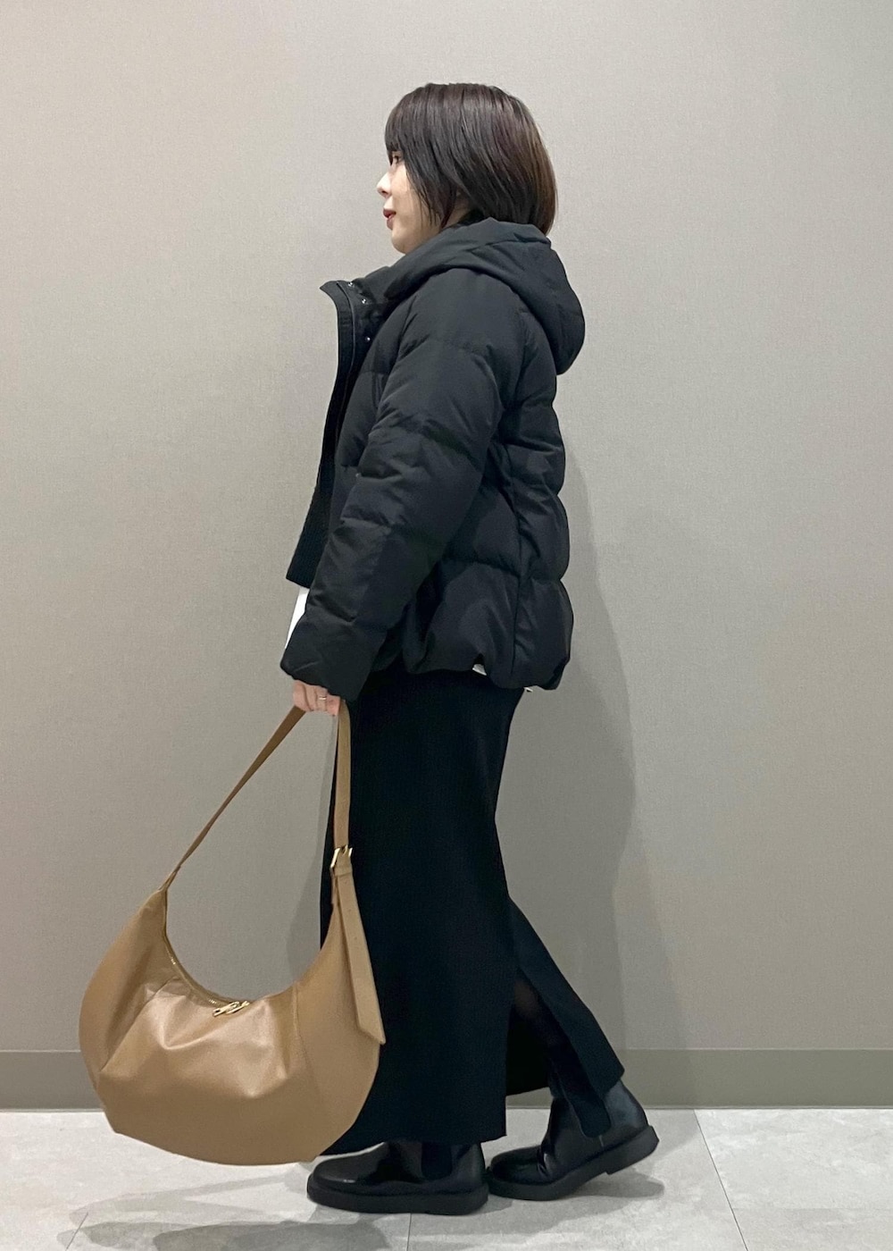 ブラック系のニット/セーター、ブラック系のスカート、ブラック系のダウンジャケット/コートを着用したレディースの冬コーディネートの2枚目の写真