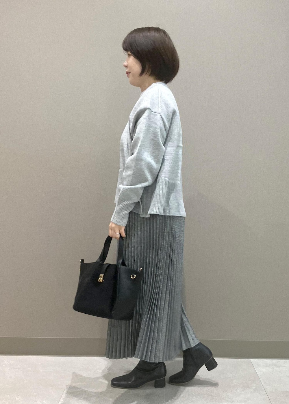 グレー系のニット/セーター、ブラック系のブーツ、ブラック系のトートバッグを着用したレディースの秋コーディネートの4枚目の写真
