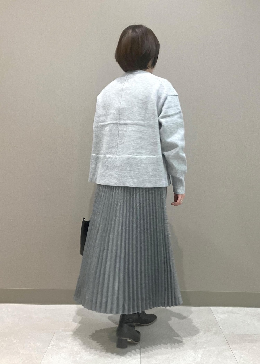 グレー系のニット/セーター、ブラック系のブーツ、ブラック系のトートバッグを着用したレディースの秋コーディネートの3枚目の写真