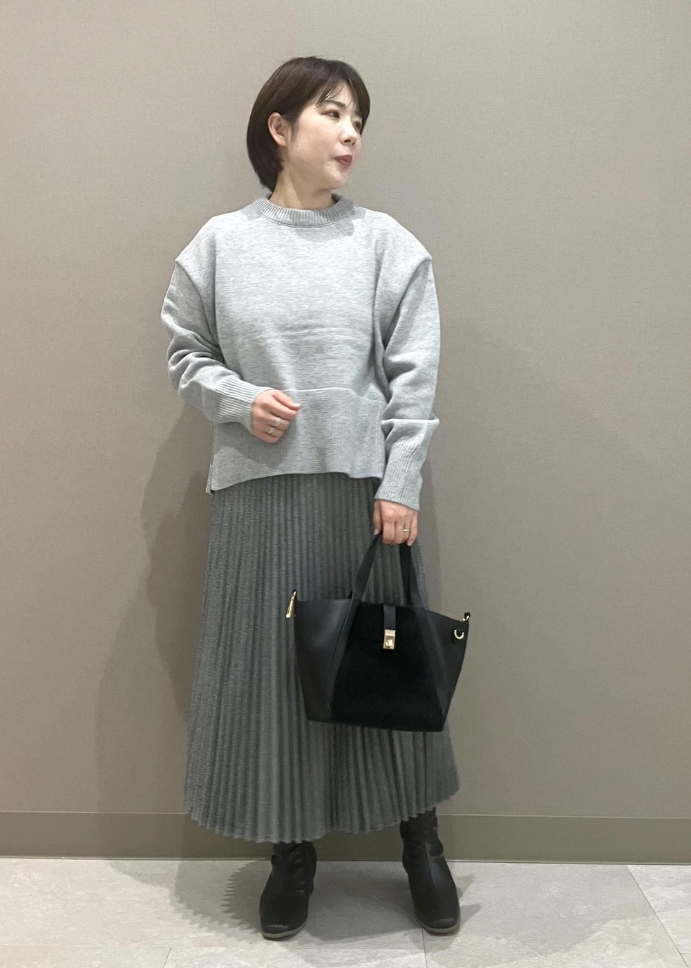 グレー系のニット/セーター、ブラック系のブーツ、ブラック系のトートバッグを着用したレディースの秋コーディネートの5枚目の写真