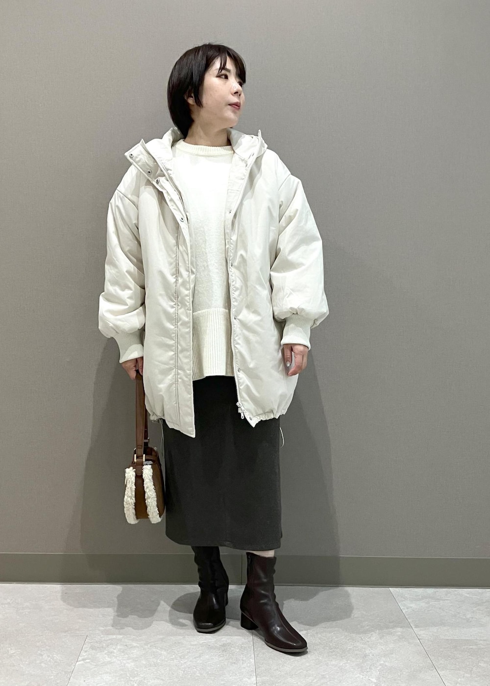 ホワイト系のニット/セーター、ブラウン系のショルダーバッグ、ブラウン系のスカートを着用したレディースの秋コーディネートの2枚目の写真