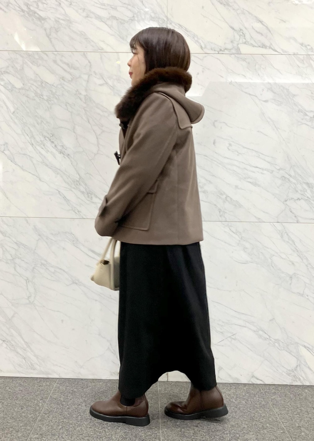 ブラック系のワンピース、ブラウン系のダッフルコート、ホワイト系のニット/セーターを着用したレディースの冬コーディネートの2枚目の写真