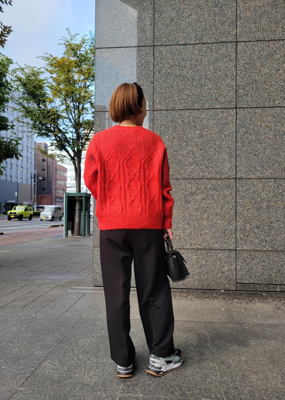 レッド系のニット/セーター、ブラック系のショルダーバッグ、ブラック系のその他パンツを着用したレディースの秋コーディネートの3枚目の写真