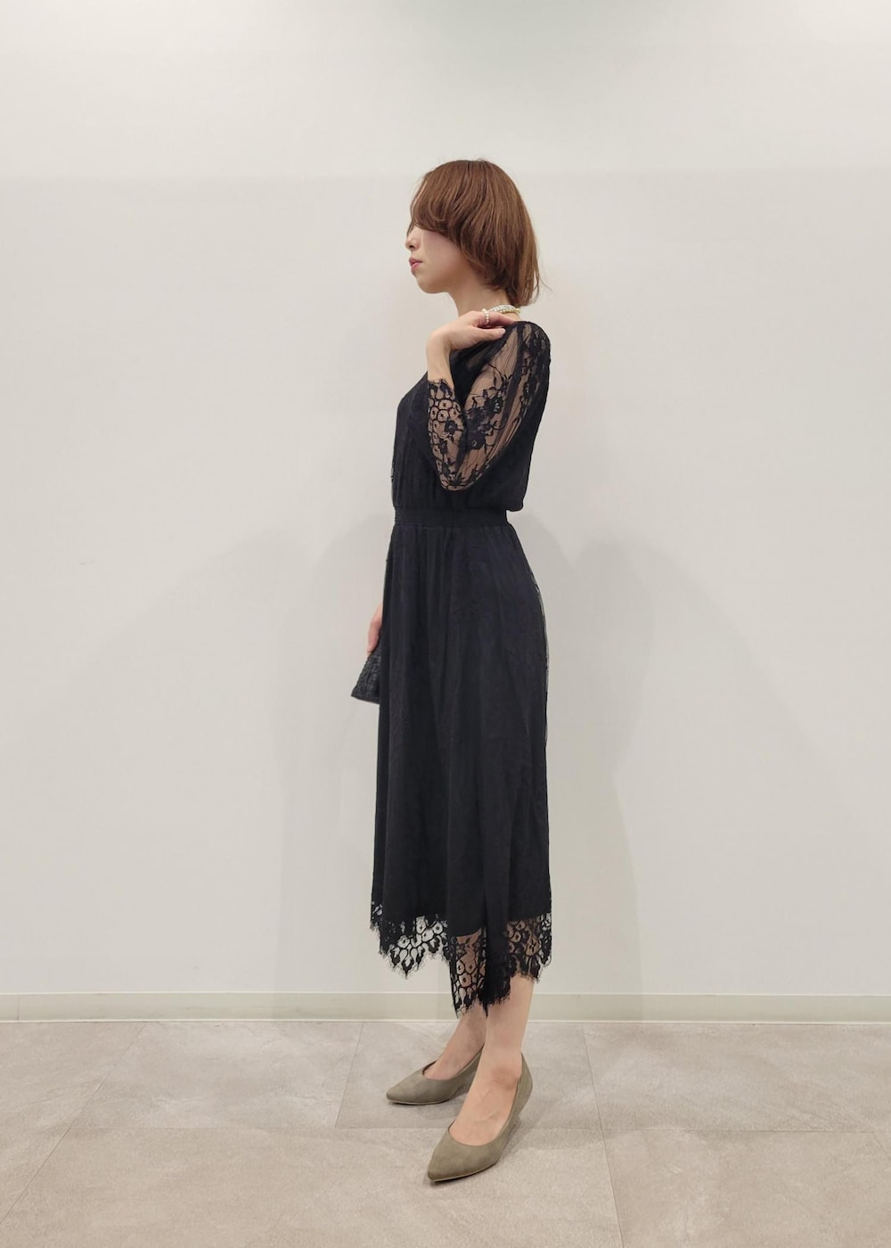 ベージュ系のパンプス、グレー系のチェスターコート、ブラック系のドレスを着用したレディースの冬コーディネートの4枚目の写真