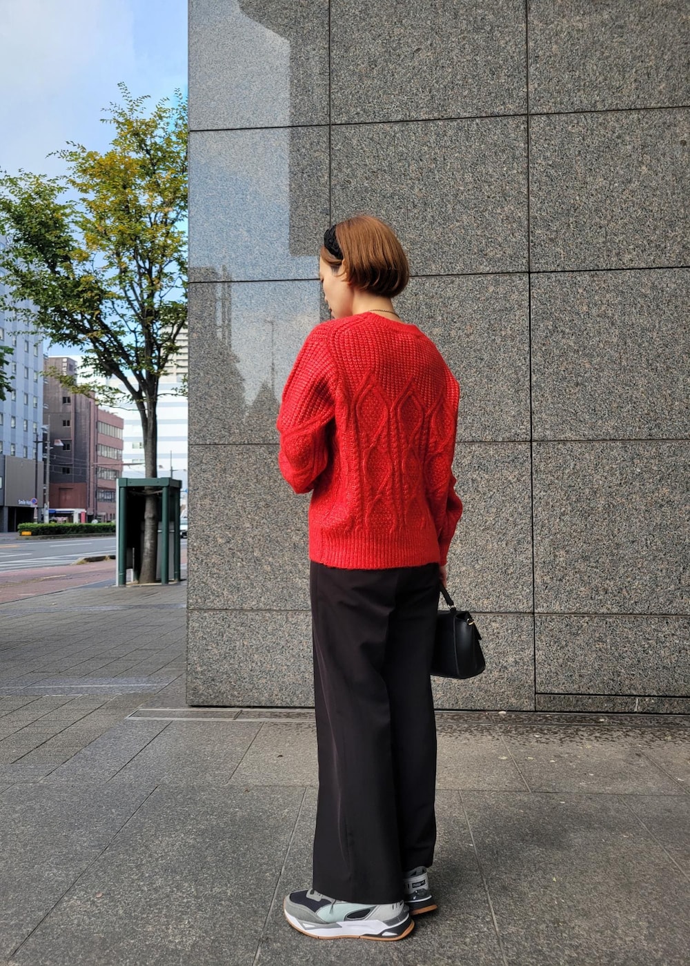 レッド系のニット/セーター、ブラック系のショルダーバッグ、ブラック系のその他パンツを着用したレディースの秋コーディネートの4枚目の写真