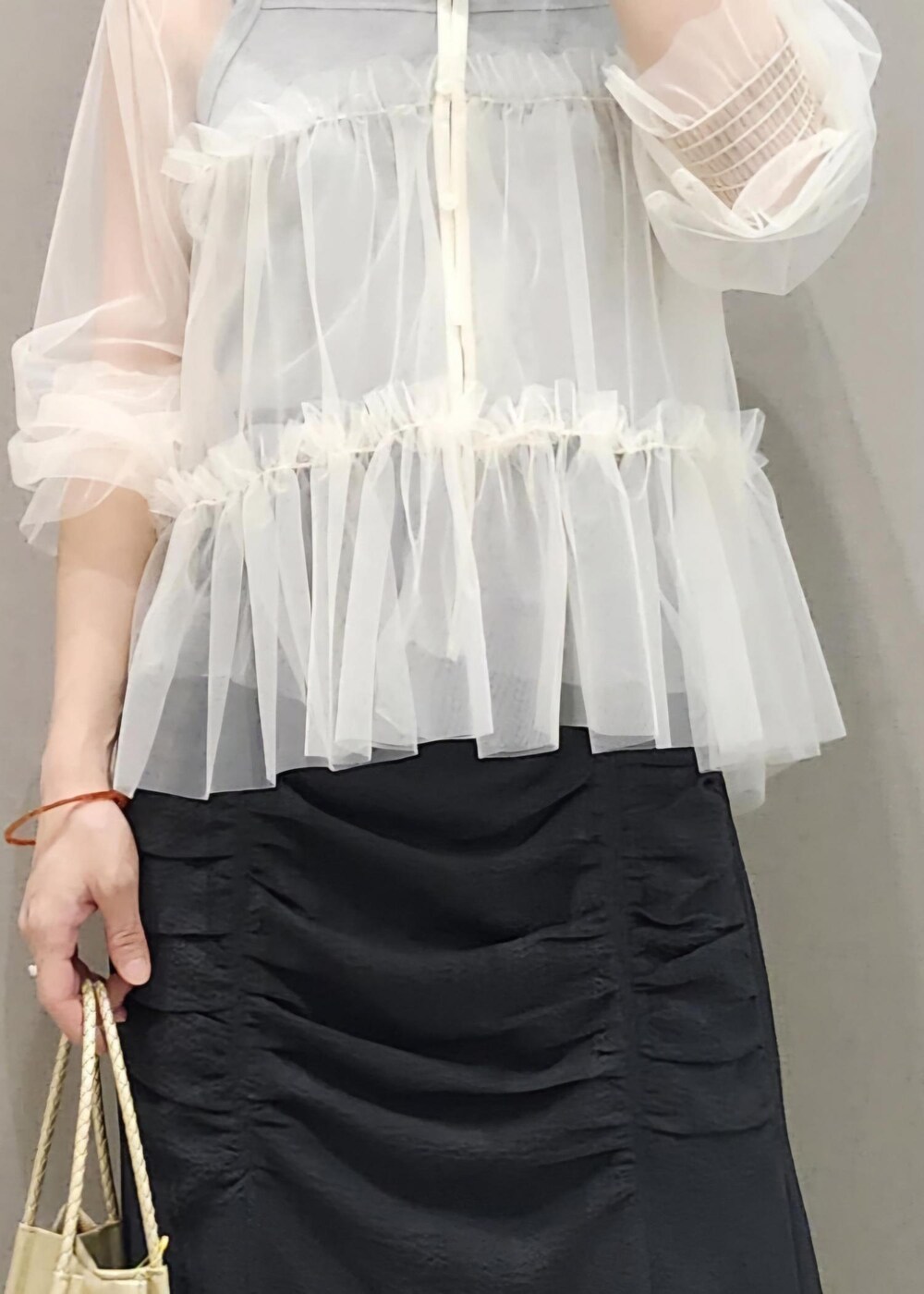 グレー系のタンクトップ、ホワイト系のカーディガン/ボレロ、ゴールド系のトートバッグを着用したレディースの夏コーディネートの9枚目の写真