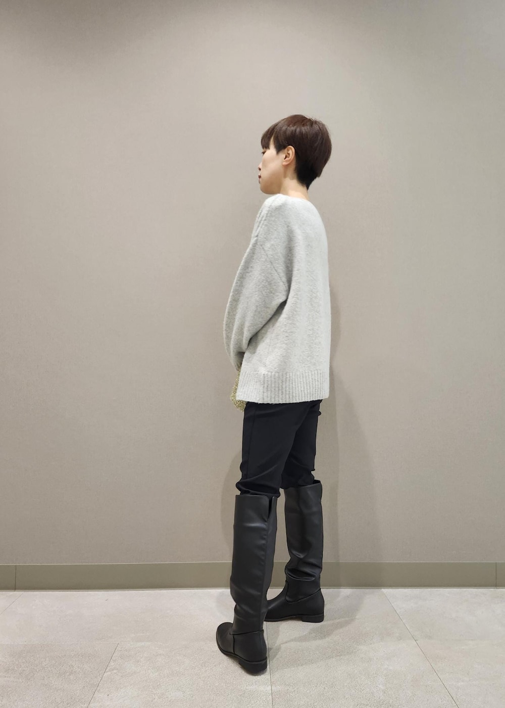 ブラック系のブーツ、ゴールド系のショルダーバッグ、グレー系のニット/セーターを着用したレディースの秋コーディネートの3枚目の写真