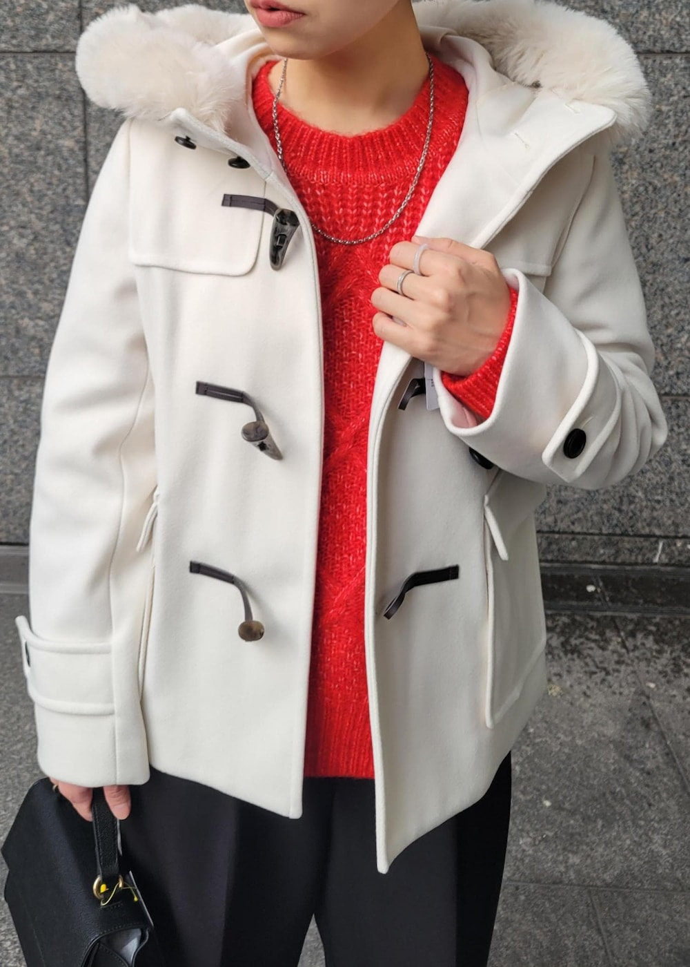 レッド系のニット/セーター、ブラック系のショルダーバッグ、ホワイト系のダッフルコートを着用したレディースの秋コーディネートの3枚目の写真