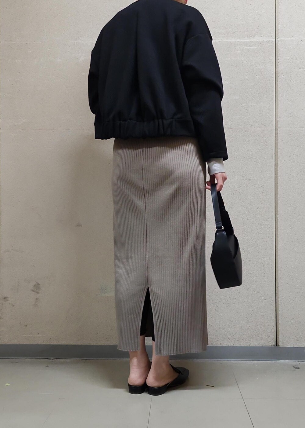 ブラック系のハンドバッグ、ブラウン系のスカート、グレー系のニット/セーターを着用したレディースの春コーディネートの4枚目の写真