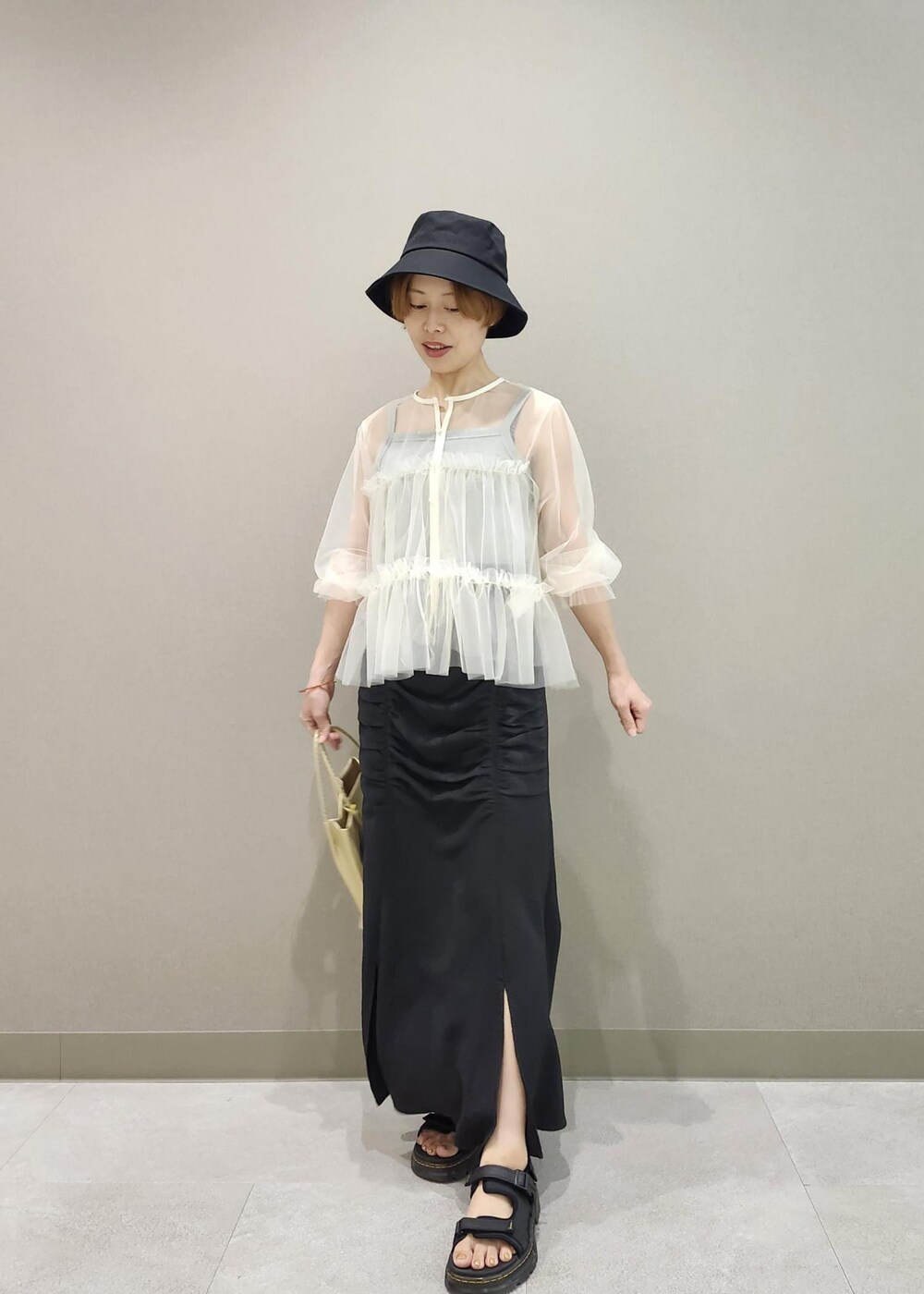 グレー系のタンクトップ、ホワイト系のカーディガン/ボレロ、ゴールド系のトートバッグを着用したレディースの夏コーディネートの6枚目の写真