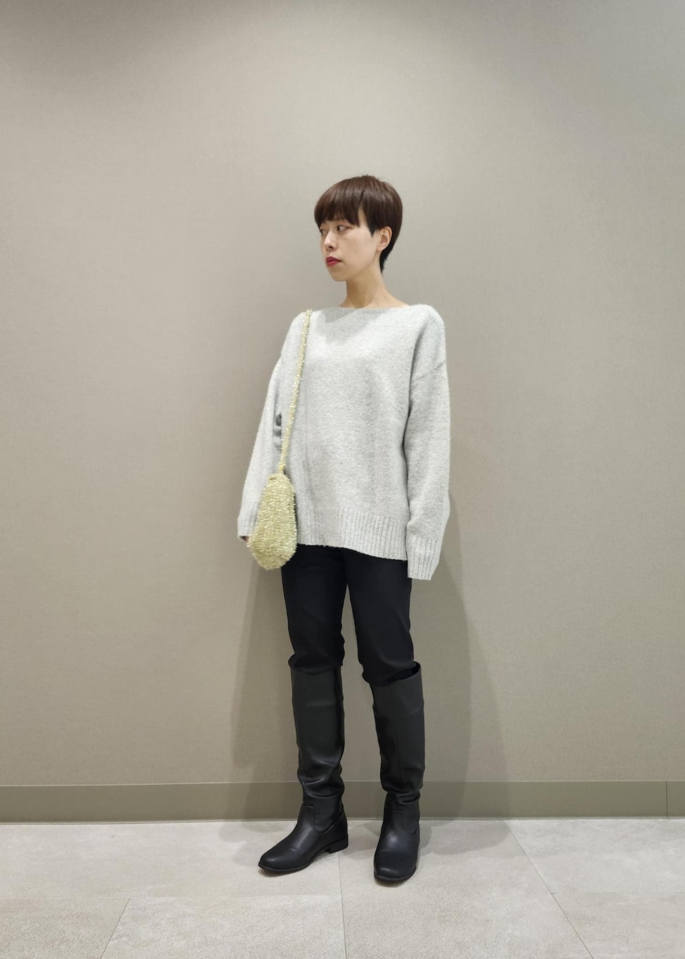 ブラック系のブーツ、ゴールド系のショルダーバッグ、グレー系のニット/セーターを着用したレディースの秋コーディネートの4枚目の写真