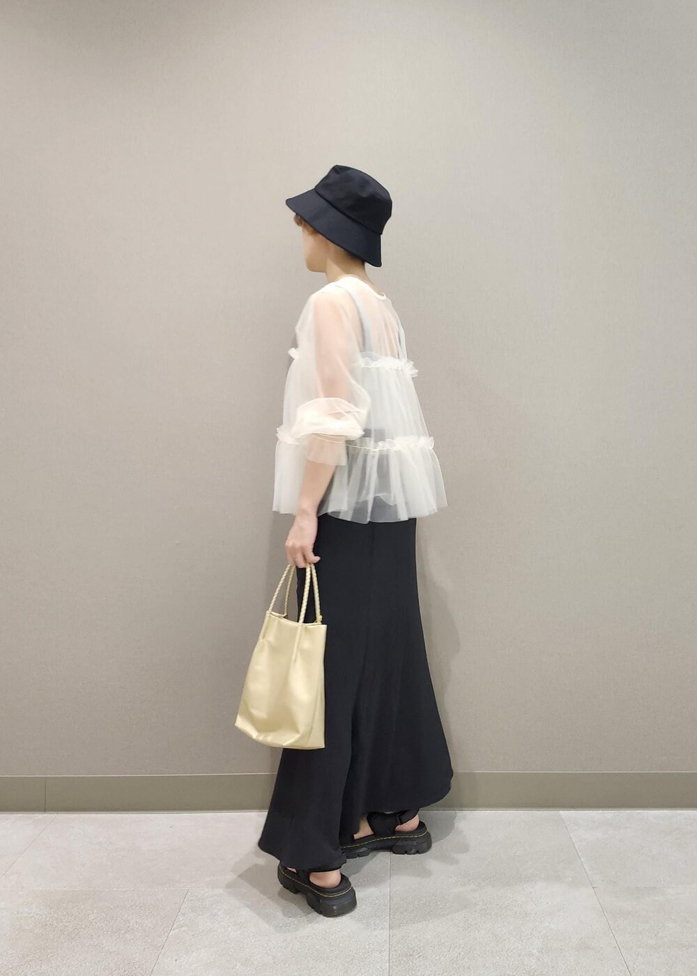 グレー系のタンクトップ、ホワイト系のカーディガン/ボレロ、ゴールド系のトートバッグを着用したレディースの夏コーディネートの7枚目の写真