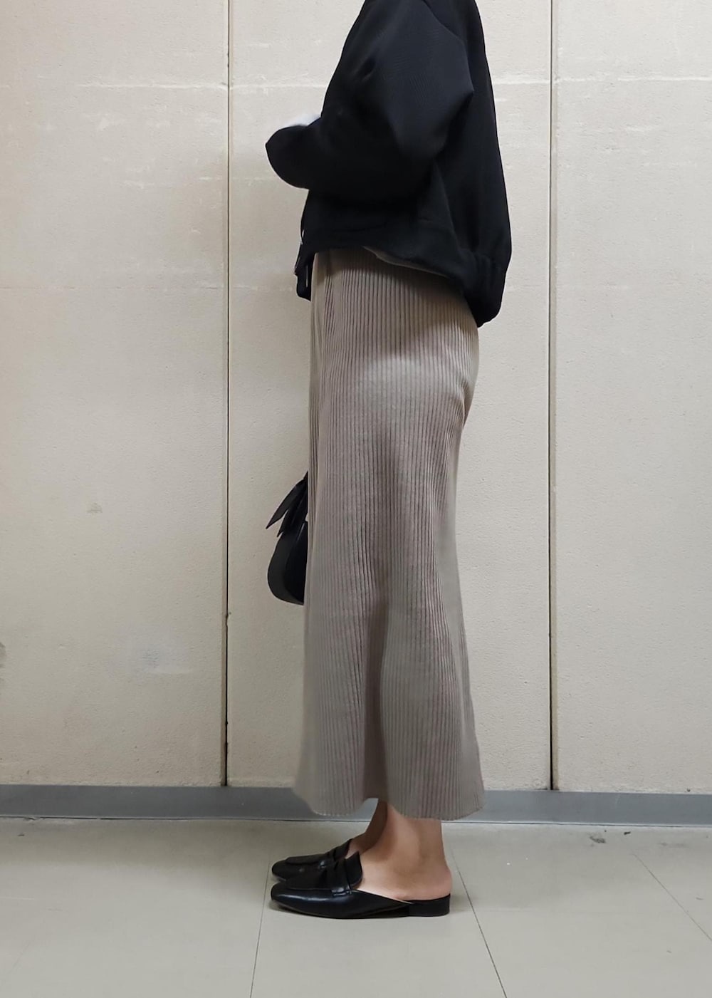 ブラック系のハンドバッグ、ブラウン系のスカート、グレー系のニット/セーターを着用したレディースの春コーディネートの3枚目の写真